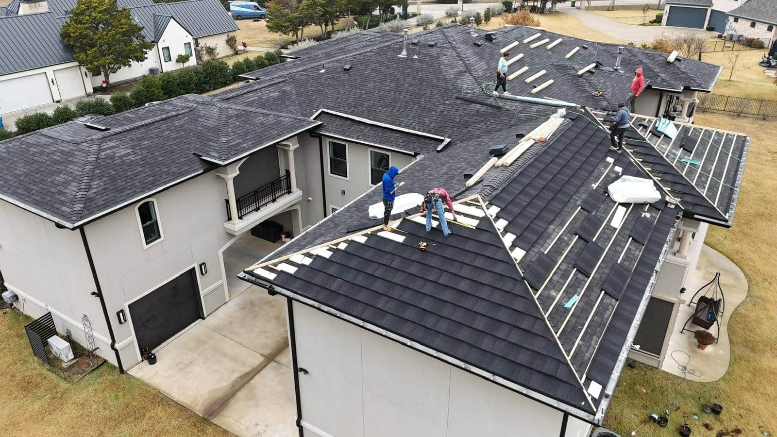 Drone view of a two-story home with a new dark shingle roof