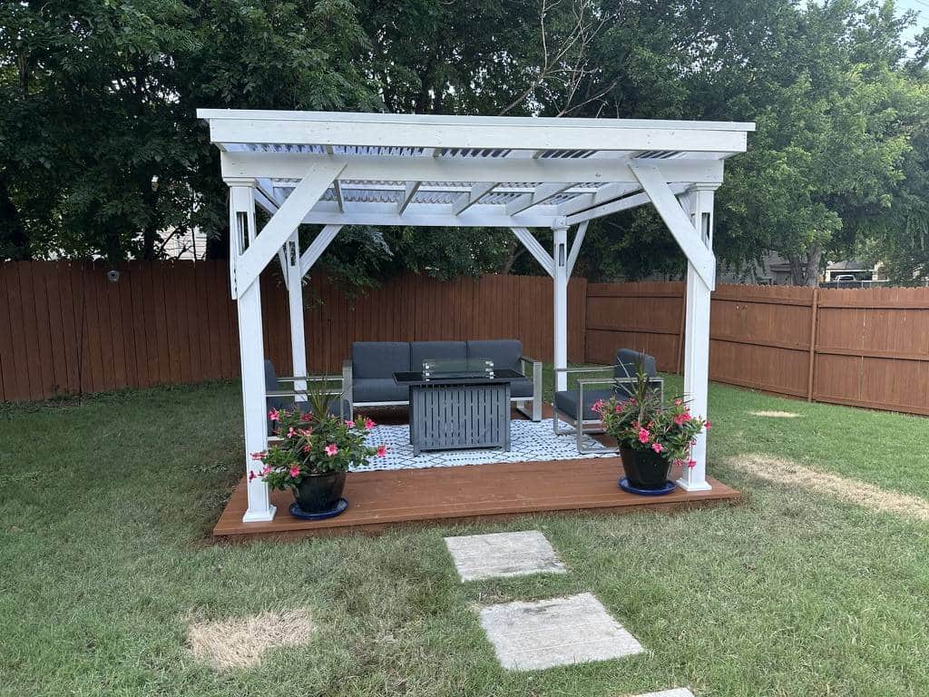 Backyard pergola and patio beside a wood privacy fence