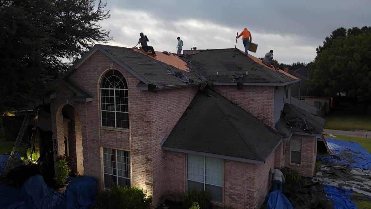 Roofing crew installing a new roof at dusk